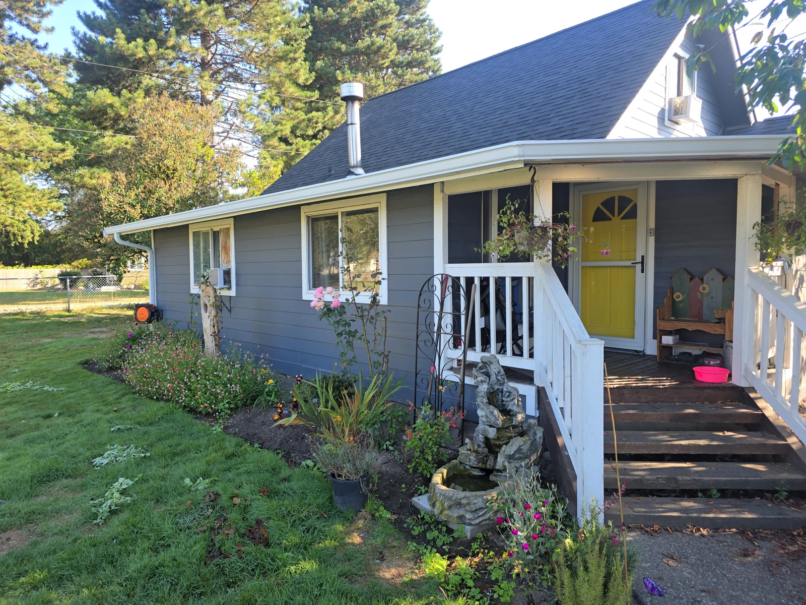 White gutters and fascia installed on cottage with dark roof shingles and white trim