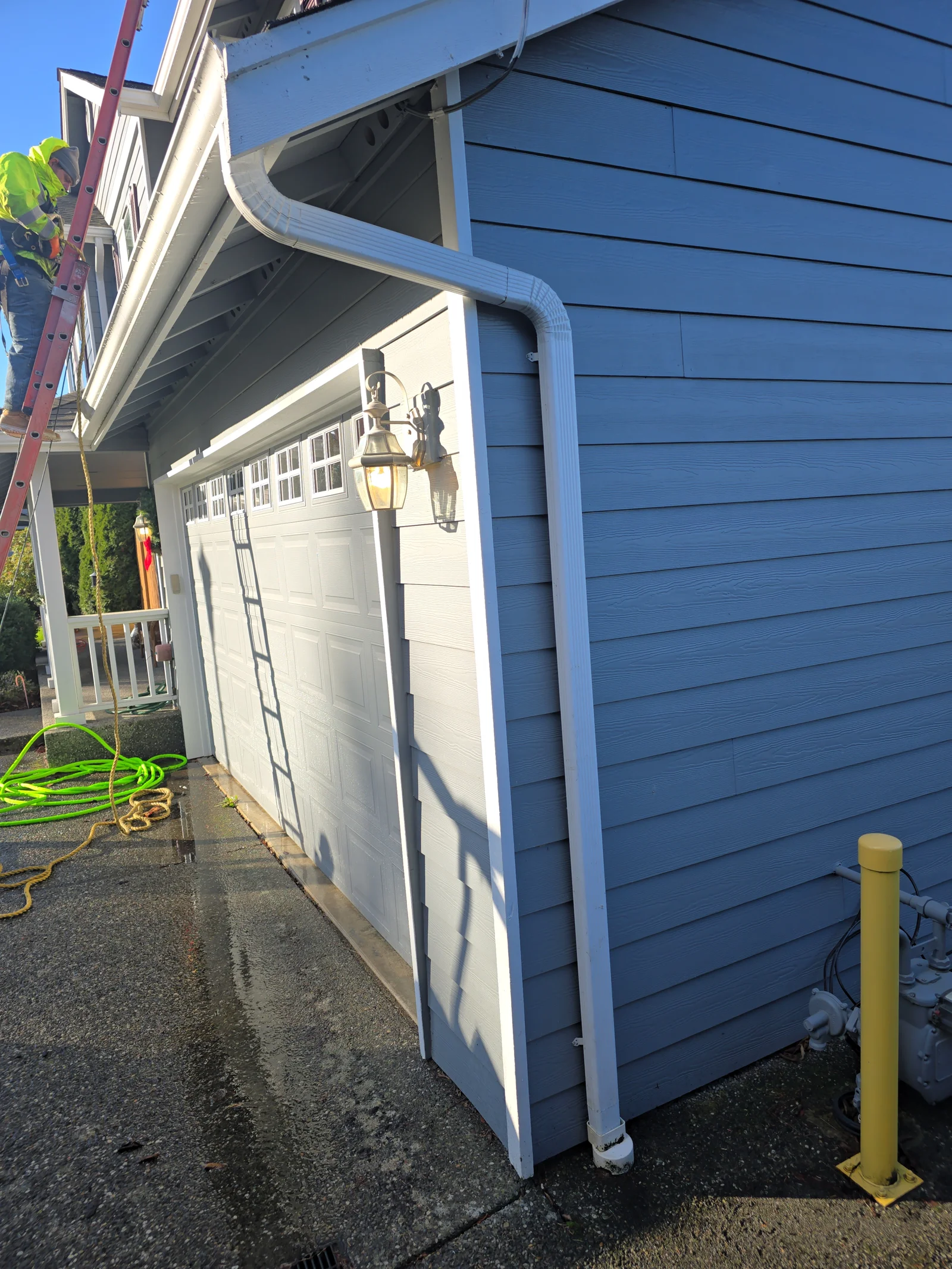 White seamless aluminum gutter and downspout on blue-sided garage with white trim