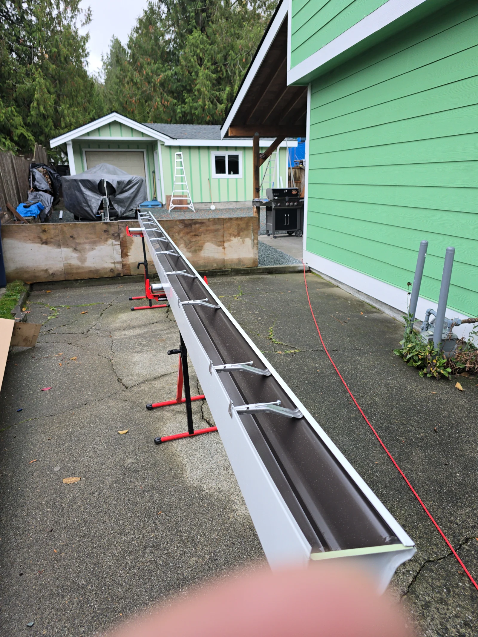 White aluminum gutters with black lining installed on residential home with drainage system