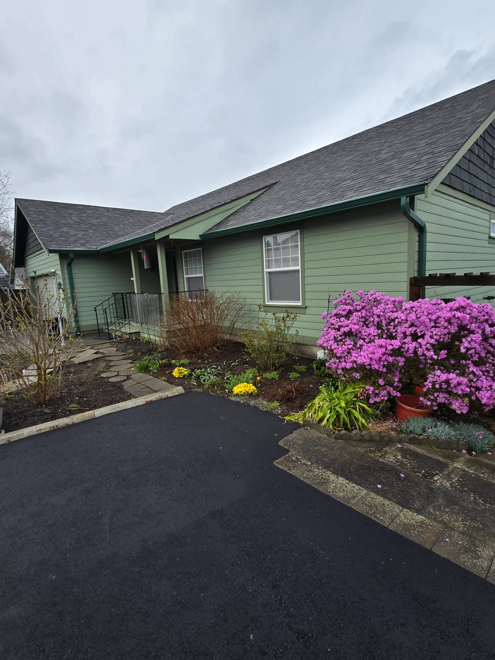Green seamless gutters and fascia installed on single-story home with dark asphalt shingle roof