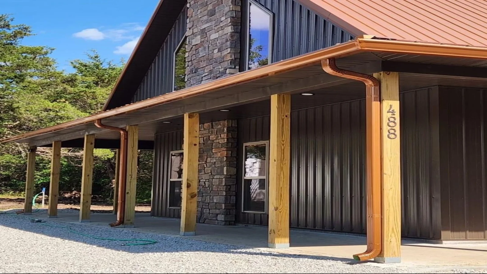 Copper gutters and downspouts on modern home with wood posts and metal siding