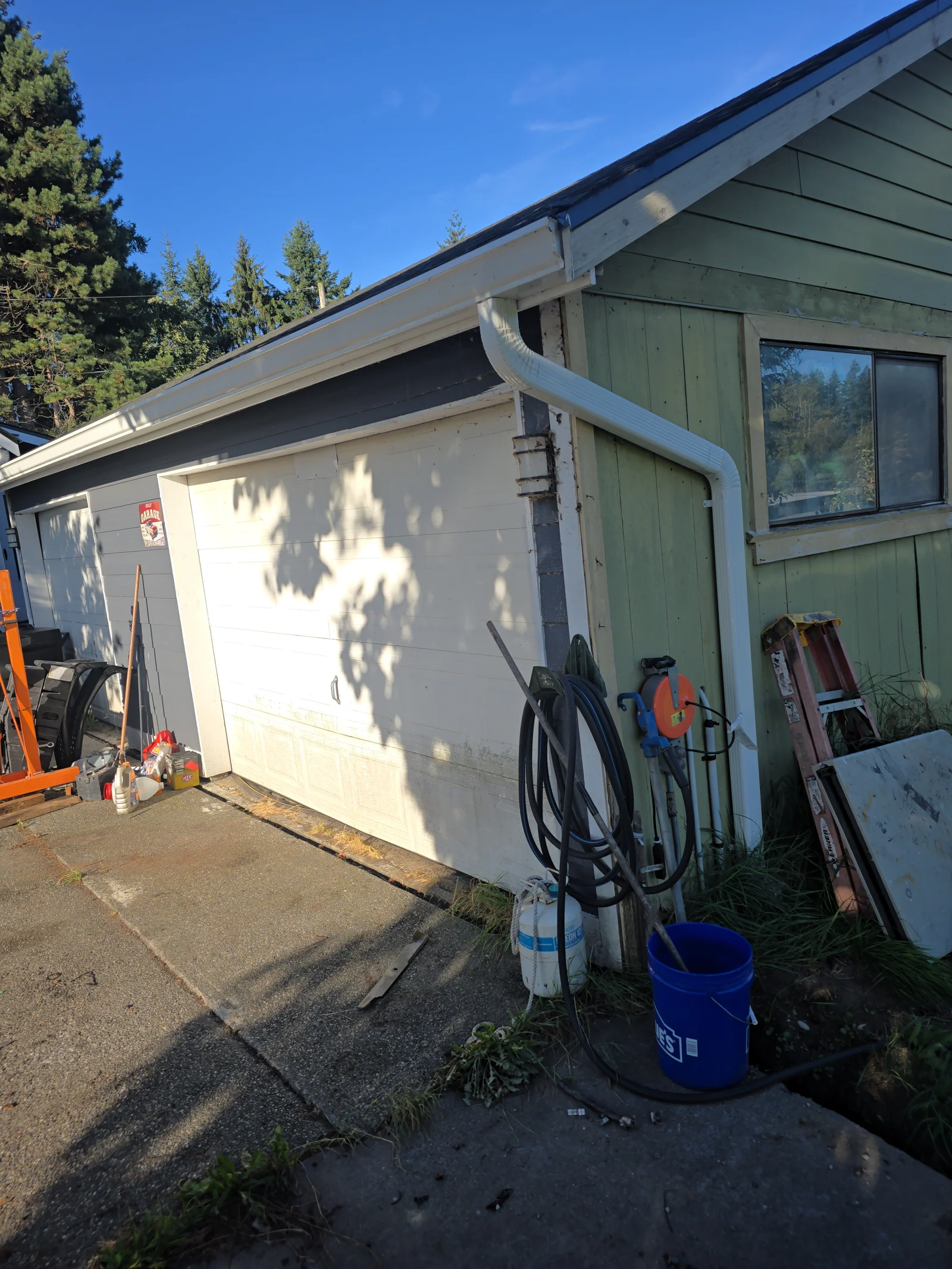 White seamless gutters and curved downspout on residential home with green siding