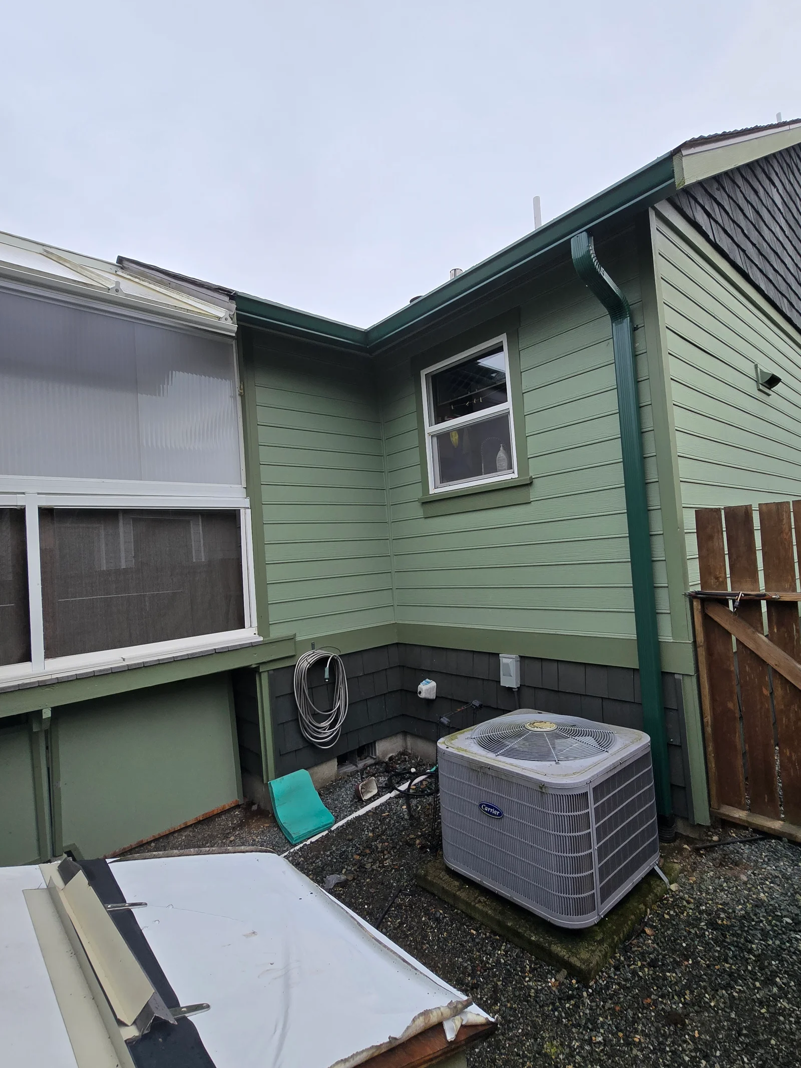 Green horizontal siding with new gutters, fascia trim, and white aluminum gutter system installed