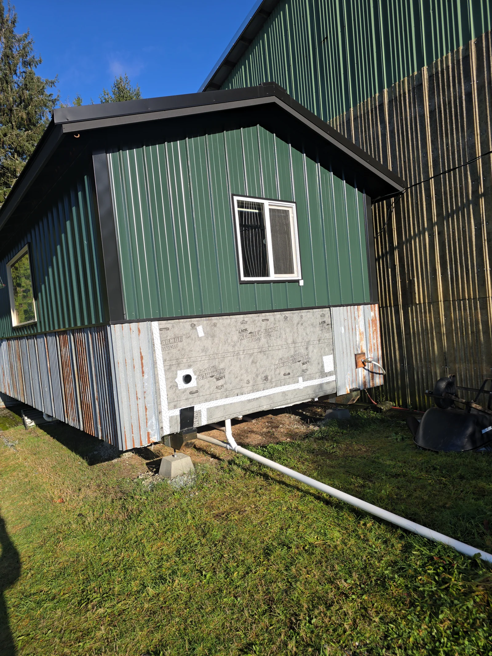 White vinyl gutter and downspout drainage system on green metal-sided residential addition