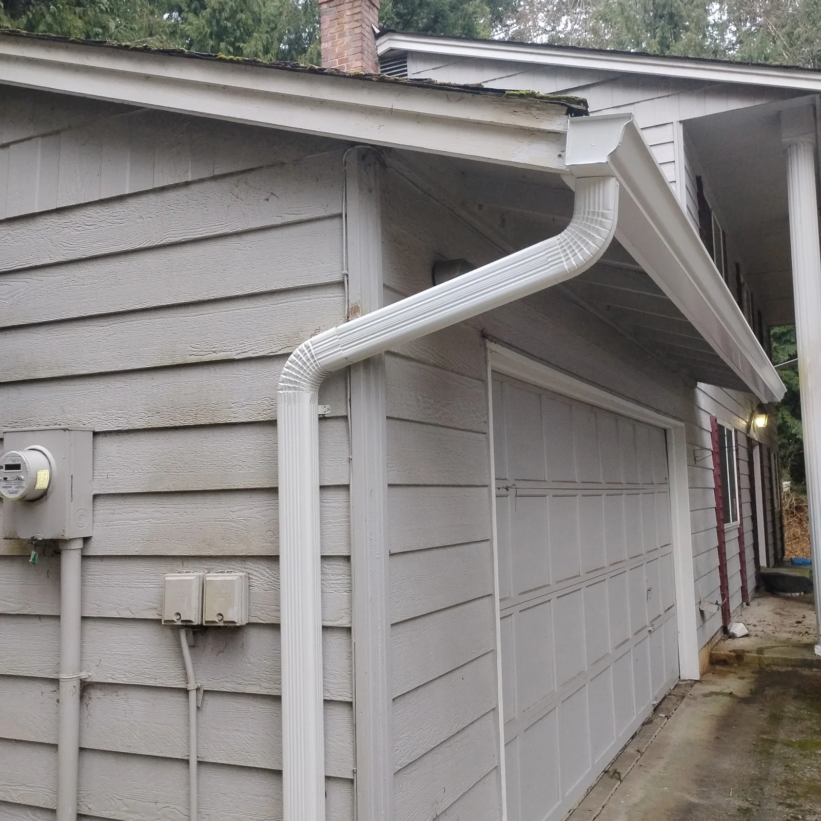 White seamless aluminum gutters and curved downspout on garage with white fascia trim
