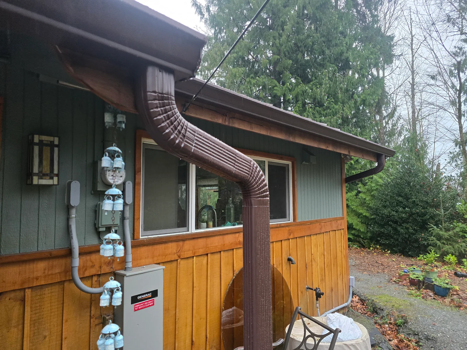 Copper ribbed downspout and gutter system on cabin with wood siding and large windows