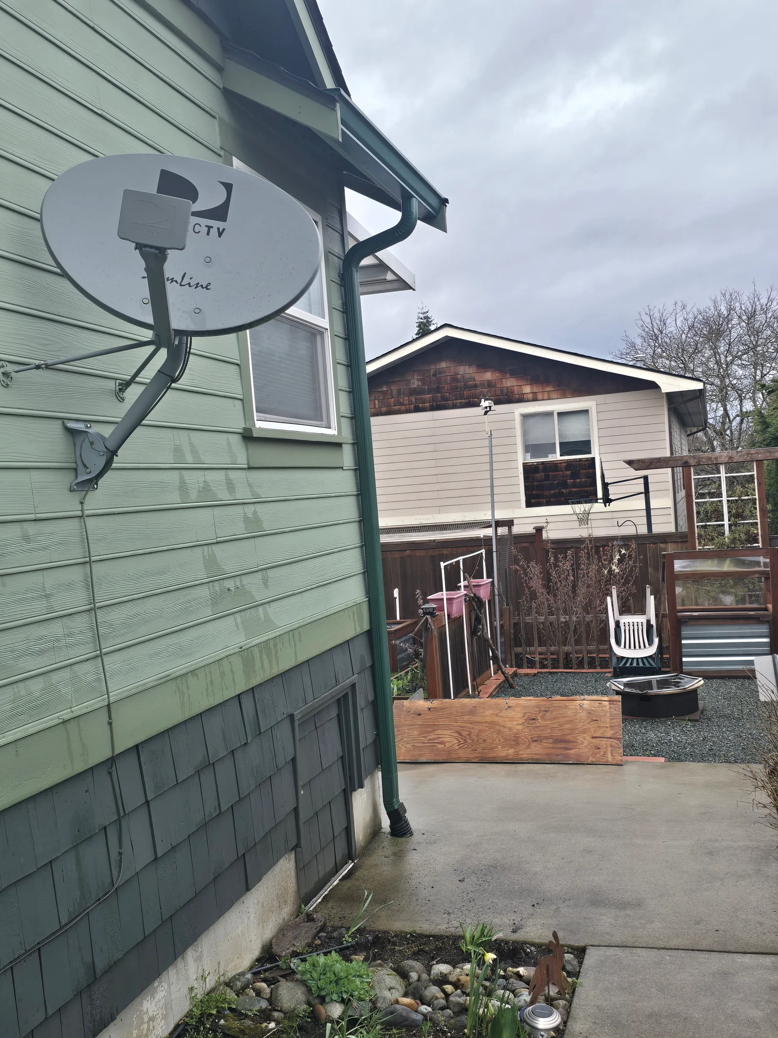 White seamless gutter with downspout installed on green horizontal siding, mobile home exterior